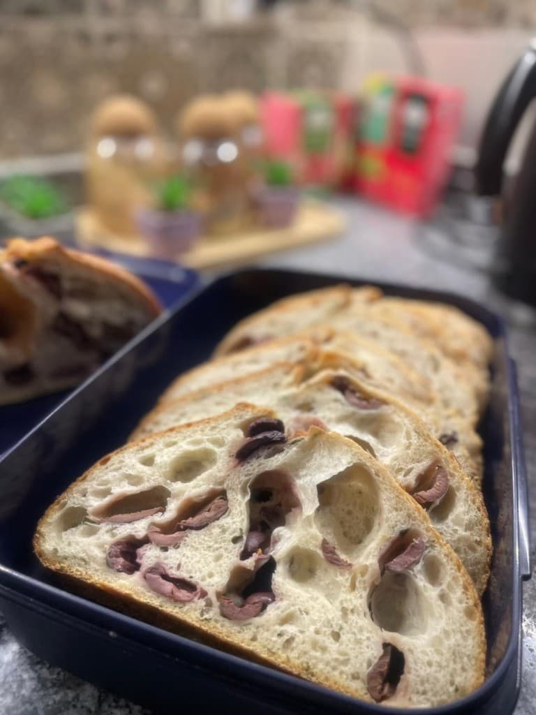 Thick slices of olive sourdough with open crumb in a dark tray